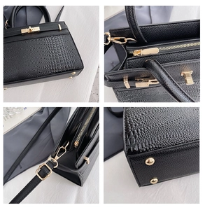 Detail view of crocodile pattern texture, gold lock, zipper, and base studs on tote bag