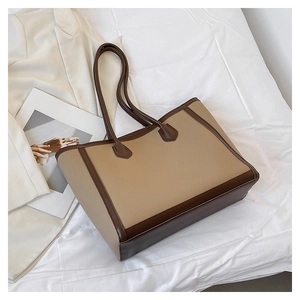 Detail of large beige and brown tote bag with pebble texture on white fabric background
