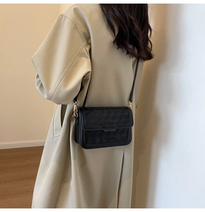 Detail of 3D geometric embossed pattern on a black minimalist flap crossbody bag