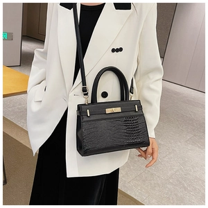 Detail of black crocodile texture tote bag on model wearing a white suit blazer