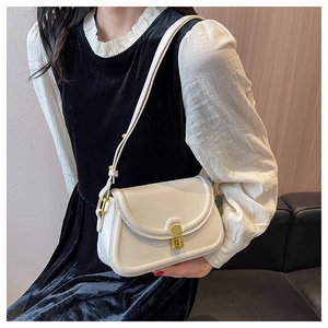 Detail of cream leather shoulder bag featuring a polished gold metal clasp and adjustable strap