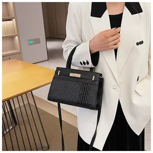 Detail of black crocodile texture leather bag with silver metal lock and top handle