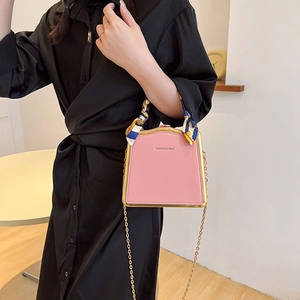 Pink fashion box bag with silk scarf handle and gold chain strap shown on a model
