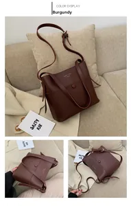 Detail of dark reddish brown bucket bag with adjustable strap and golden logo text