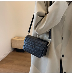 Detailed view of black crossbody bag featuring 3D geometric cube embossed texture