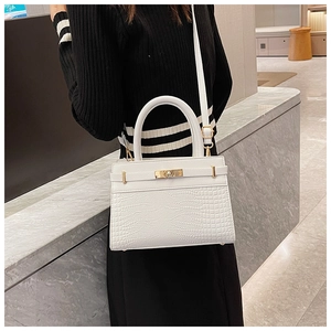 Close-up of white crocodile pattern texture and golden metal twist-lock on the bag