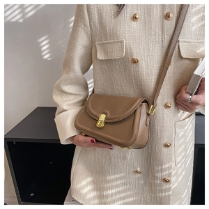 Close-up of a vintage brown leather crossbody bag with elegant gold metal buckle detail