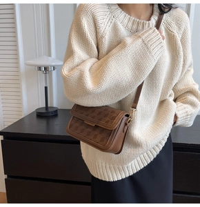 Close-up of brown textured leather crossbody bag with geometric embossed pattern details