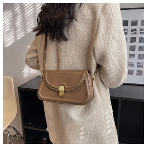 Detail of vintage brown leather crossbody bag with golden clasp and curved flap