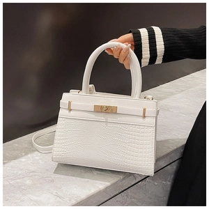 Detail of white crocodile pattern tote with a gold twist lock on marble surface