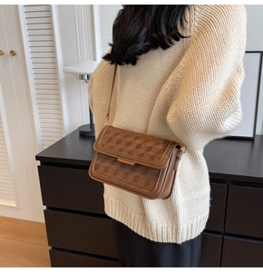 Detailed view of brown crossbody bag featuring geometric embossing and adjustable strap
