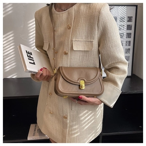 Close-up of brown leather crossbody bag with elegant gold twist lock on tweed jacket