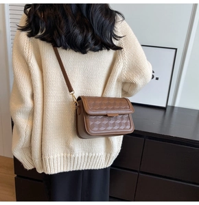 Detail view of deep brown leather crossbody bag with 3D geometric embossed pattern