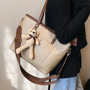 Minimalist large tote bag in beige and brown leather with teddy bear charm on model
