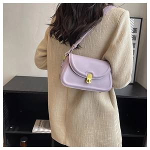 Close-up of a lilac half-moon shoulder bag with a gold buckle worn by a model