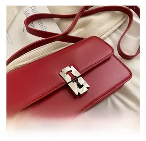 Detail of red leather saddle bag featuring a high-gloss silver metal buckle and fine stitching