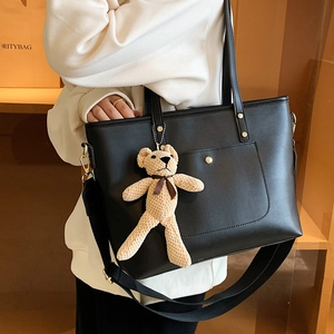 Minimalist black tote bag in matte faux leather with brown bear charm and wide strap