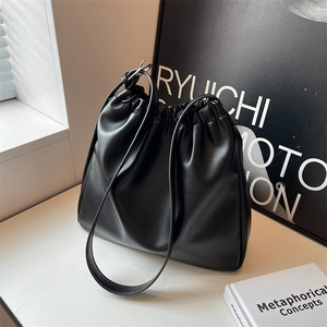 Minimalist black soft leather hobo bag with drawstring closure on white table