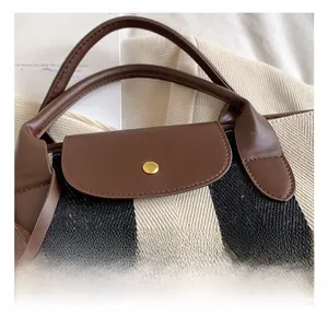 Détail du cabas en toile rayée avec rabat en cuir marron et bouton doré en métal