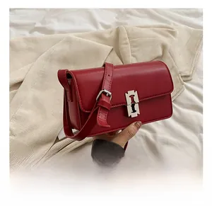 Detail of red leather saddle bag showing modern silver buckle and smooth texture finish