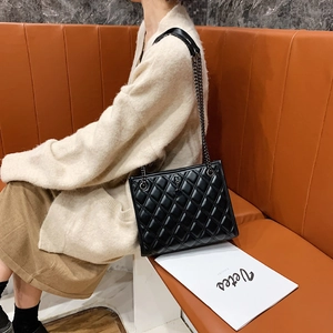 Quilted black leather shoulder bag with sleek metal chain strap shown in a lifestyle setting