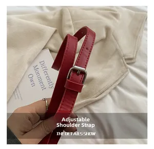 Detail of red PU leather adjustable shoulder strap with silver metal buckle and holes