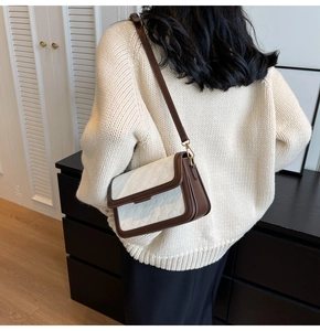 Close-up of a stylish square crossbody bag in brown and white leather with geometric embossing