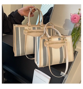 Detail of striped canvas tote bag showing two sizes with premium leather trim handles