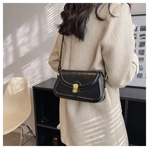 Chic black vintage shoulder bag shown on model in a minimalist modern interior setting