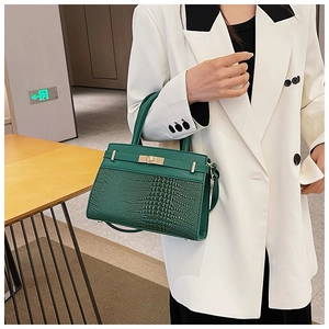 Detail showing dark green crocodile texture leather bag with gold metal buckle and handle