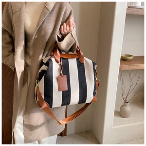 Détail d'un grand sac fourre-tout en toile rayée avec poignées en cuir marron par un mannequin