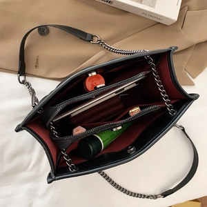 Black quilted shoulder bag with contrast red lining and multi-compartment interior
