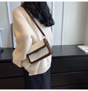 Side view of woman wearing a cream textured flap bag with brown trim and slim strap