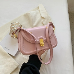 Close-up of a soft pink leather crossbody bag with a polished gold metal twist lock