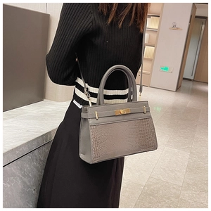 Close-up of grey handbag featuring crocodile texture and golden metal twist lock detail