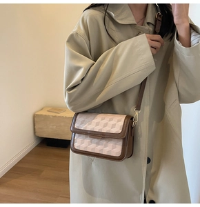 Detail of minimalist beige geometric 3D pattern bag with brown leather trim and gold hooks