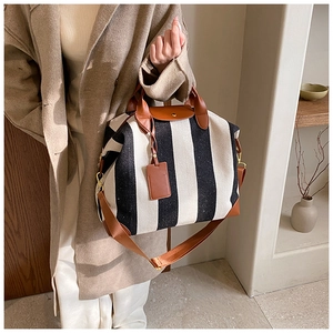 Détail du sac cabas à rayures noires et blanches avec finitions en cuir brun et bouton