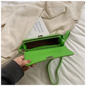 Detail of neon green saddle bag showing silver twist lock and spacious interior
