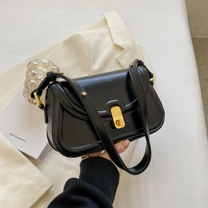 Detail of black leather crossbody bag featuring gold metal lock and shoulder strap