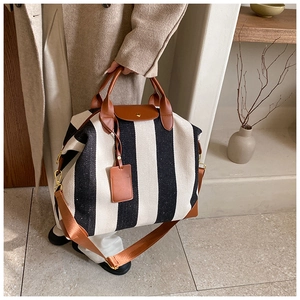 Détail du sac de voyage en toile rayée avec poignées en cuir marron et boucles en métal