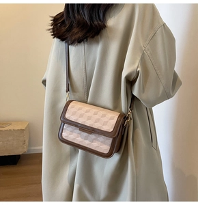 Detail of beige geometric 3D pattern on leather crossbody bag with brown trim straps