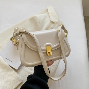 Close-up of cream leather shoulder bag with gold twist lock and wavy transparent handle