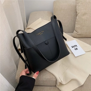 Classic black leather bucket bag with gold lettering shown on a beige sofa