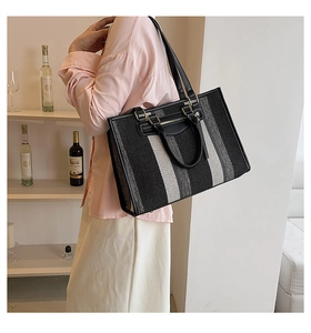 Detail of striped woven tote bag featuring dual leather handles and large capacity