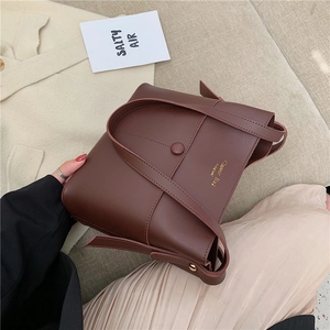 Minimalist dark brown leather bucket bag with a round buckle decoration and top handle