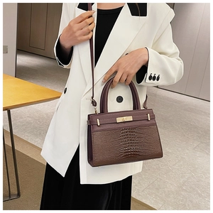 Close-up of crocodile-embossed leather texture and gold twist lock on women bag