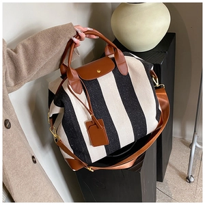 Détail du sac fourre-tout en toile rayée avec anses en cuir marron et finitions dorées