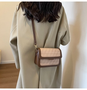 Detail of a retro crossbody bag featuring a 3D geometric pattern and brown leather trim
