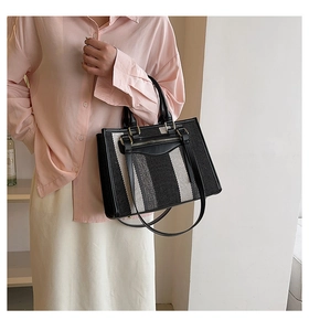 Detail of canvas tote bag with black and white vertical stripes and leather patchwork trim