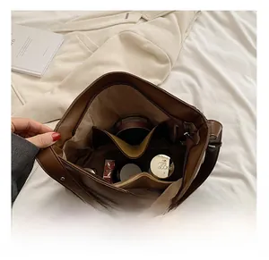 Detail view showing interior capacity with multiple pockets and cosmetics inside a brown bag